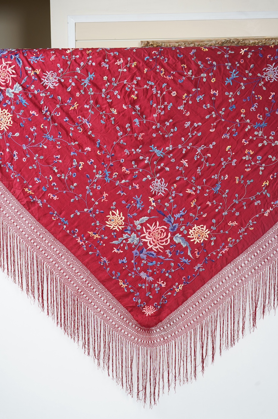 A late 19th early 20th century Chinese silk polychrome embroidered shawl on a maroon silk background. Fringed. 180cm x 60cm. Condition - no fading to colours, silk good